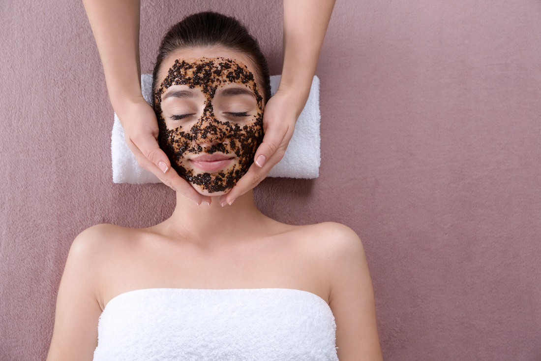 Beautiful young woman with scrub mask in spa salon