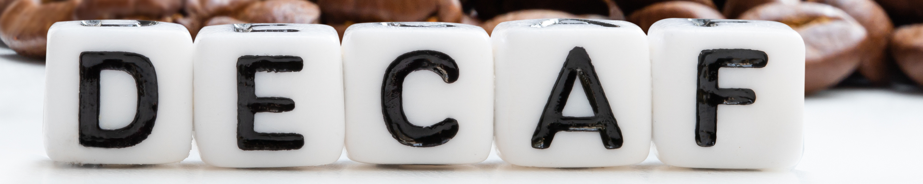 Roasted coffee beans scattered out of the bag. Concept of decaf coffee / Elena Zajchikova Roasted coffee beans scattered out of the bag. Concept of decaf coffee