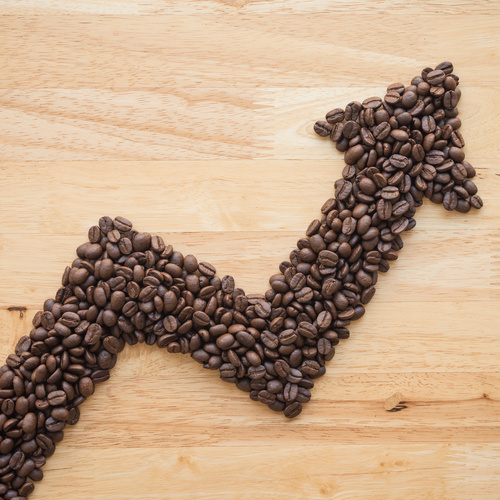 Coffee roast arabica bean as graph chart soar rising up on wooden background. Coffee bean price hike increase in commodity trading market, inflation crisis, investment concept.