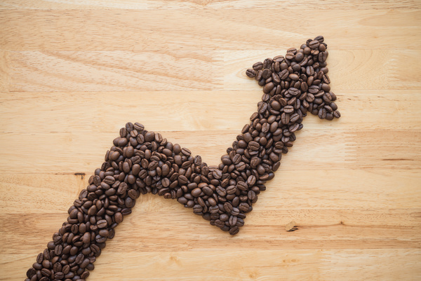 Coffee roast arabica bean as graph chart soar rising up on wooden background. Coffee bean price hike increase in commodity trading market, inflation crisis, investment concept.