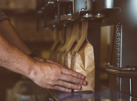 Unrecognizable male arms putting wrapped coffee beans in row